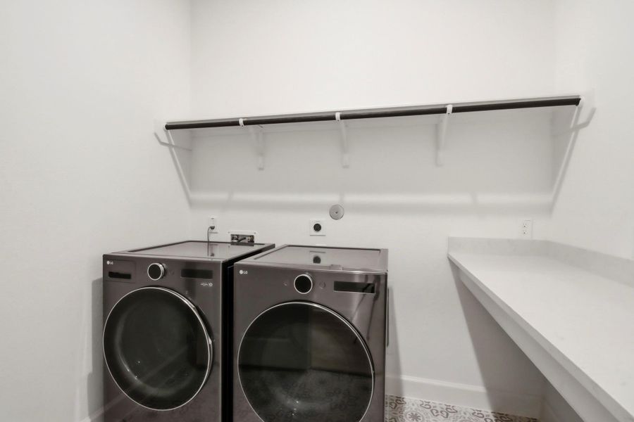 Efficient laundry room outfitted with sleek front-loading appliances, ample shelving, and a convenient folding counter for added functionality.