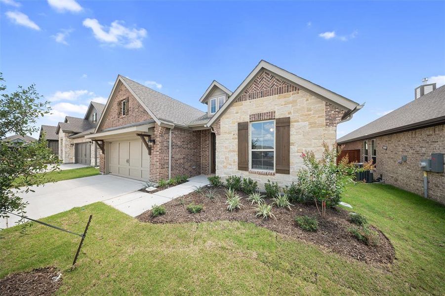 View of front of house featuring driveway, a front yard, stone siding, brick siding, and a shingled roof