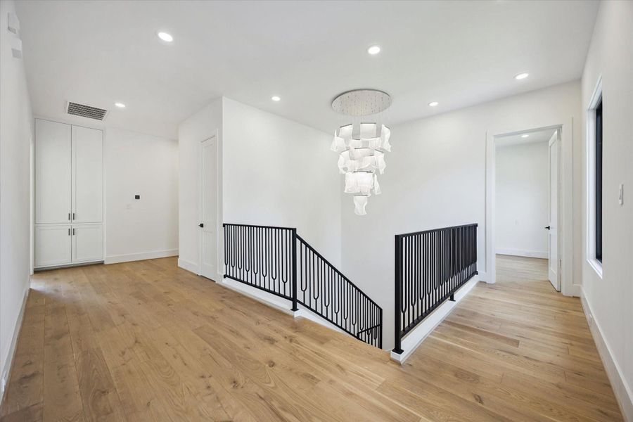 Upstairs spacious landing area is adorned with an oversized designer chandelier and modern railing, leading to the secondary bedrooms, game room and primary suite. Upstairs spacious landing area is adorned with an oversized designer chandelier and modern railing, leading to the secondary bedrooms, game room and primary suite.