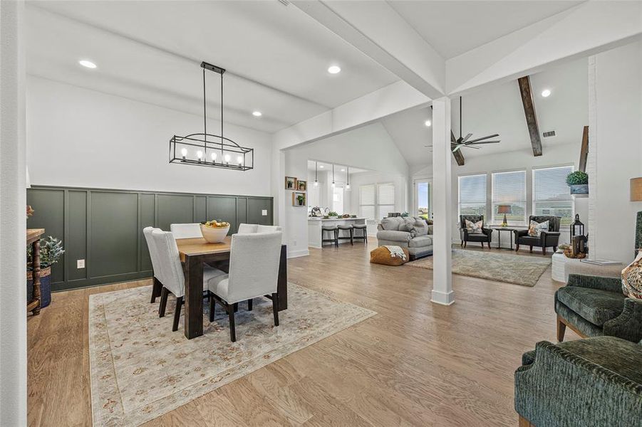 Dining area featuring beam ceiling, light hardwood / wood-style flooring, ceiling fan with notable chandelier, and high vaulted ceiling