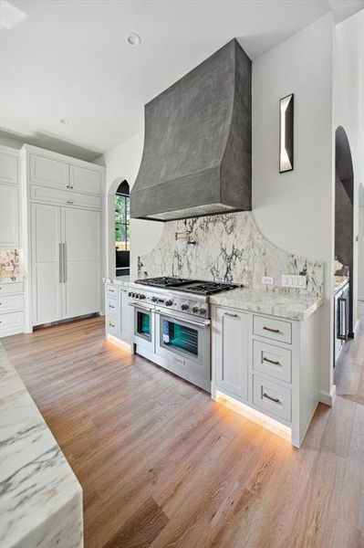 A chef's dream with this 48" Thermador range and 48” vent hood liner with custom plaster surround, pot filler, and marble backsplash showcases both functionality and style.