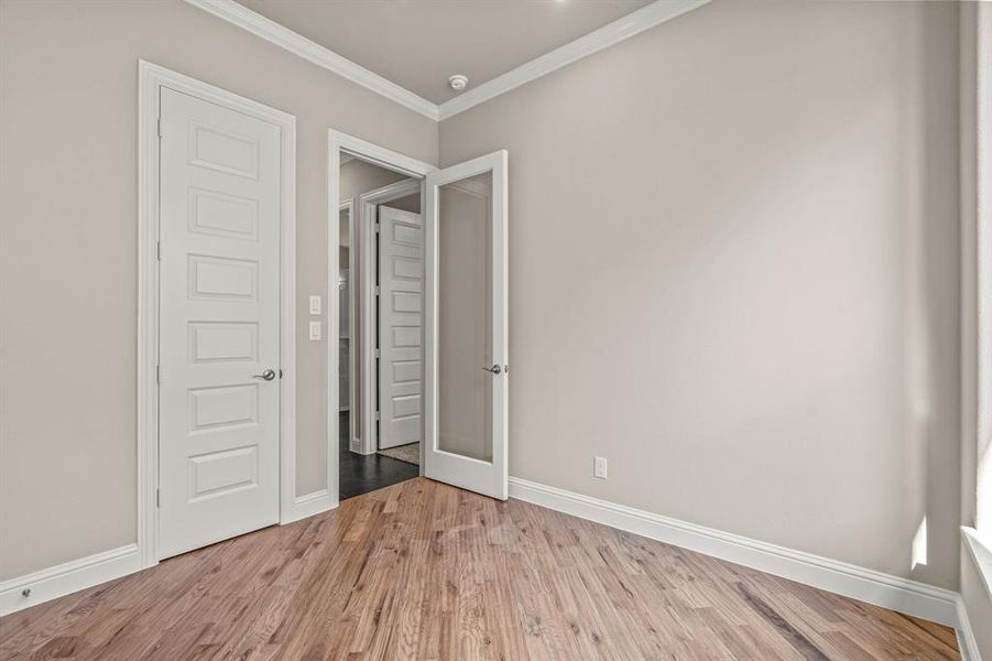 Unfurnished bedroom featuring wood finished floors and crown molding Unfurnished bedroom featuring wood finished floors and crown molding