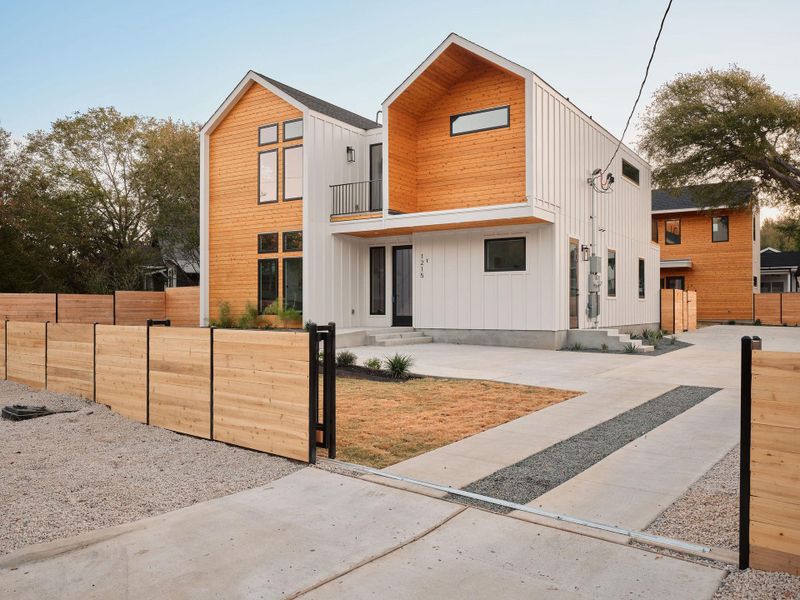 Contemporary house featuring board and batten siding, a balcony, and concrete driveway Contemporary house featuring board and batten siding, a balcony, and concrete driveway