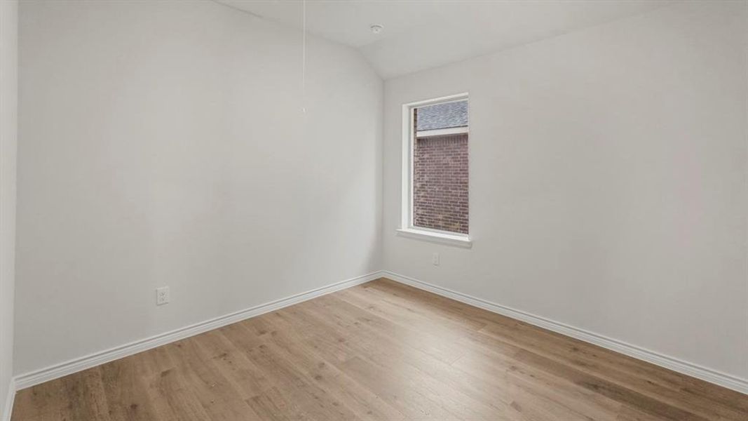 Spare room with wood finished floors and vaulted ceiling Spare room with wood finished floors and vaulted ceiling