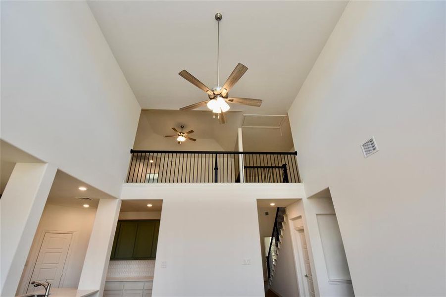 Staircase with ceiling fan and a towering ceiling