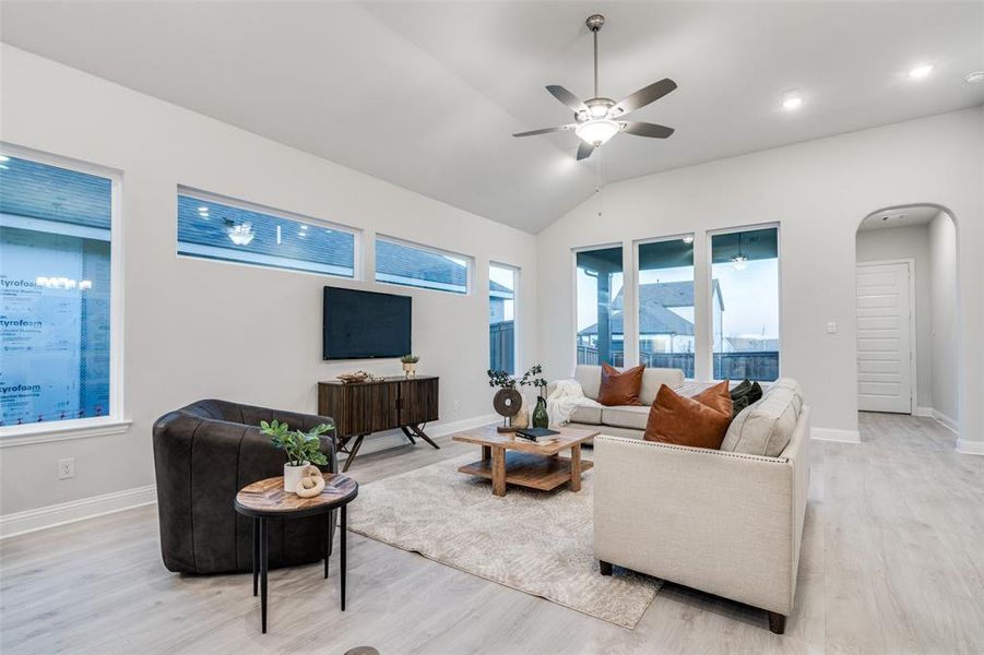 Living room with ceiling fan, light hardwood / wood-style floors, and vaulted ceiling