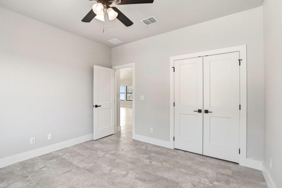 A well-lit bedroom features cool-toned tile flooring and ample closet space for comfortable living. A well-lit bedroom features cool-toned tile flooring and ample closet space for comfortable living.