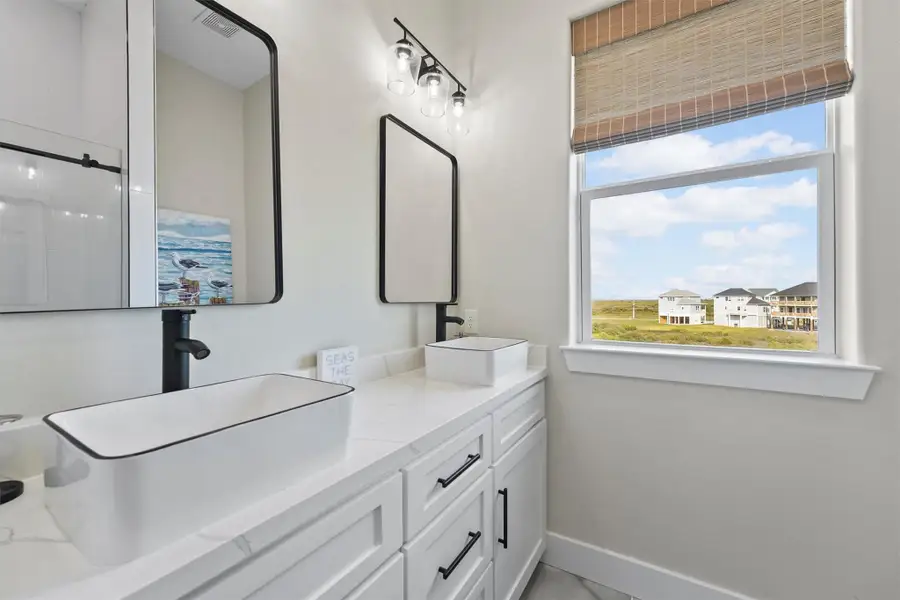 The bunkroom ensuite bathroom is bright and modern bathroom with dual sinks, sleek black fixtures, and large mirrors.