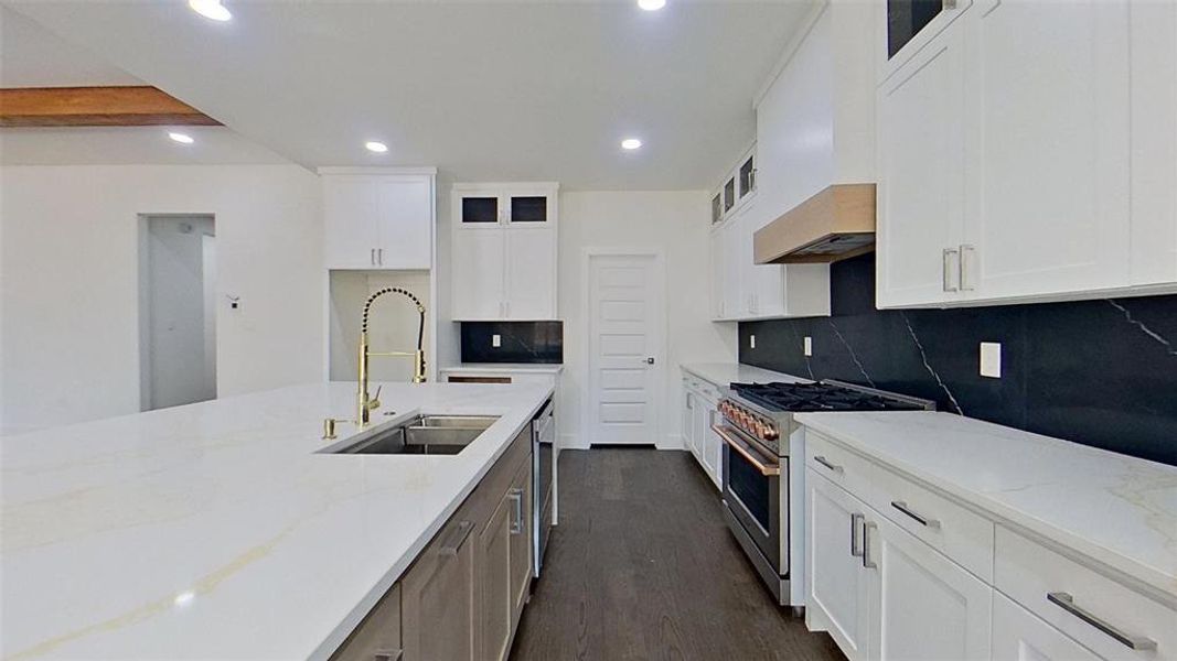 Kitchen with high end range, light stone countertops, dark wood finished floors, glass insert cabinets, and recessed lighting