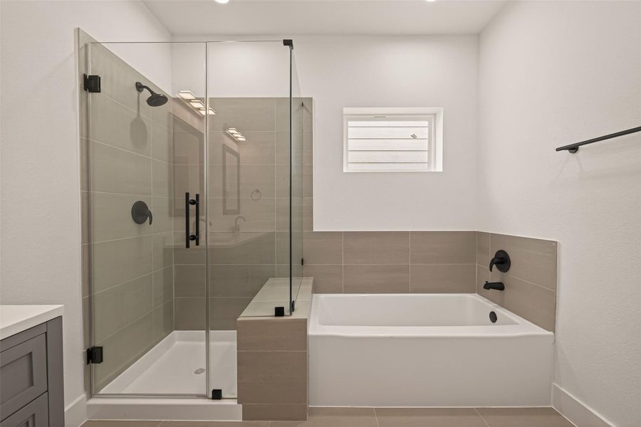 This modern bathroom features a sleek glass-enclosed shower and a separate bathtub, both with matte black fixtures. The neutral tiles and bright lighting create a clean, contemporary look. This modern bathroom features a sleek glass-enclosed shower and a separate bathtub, both with matte black fixtures. The neutral tiles and bright lighting create a clean, contemporary look.