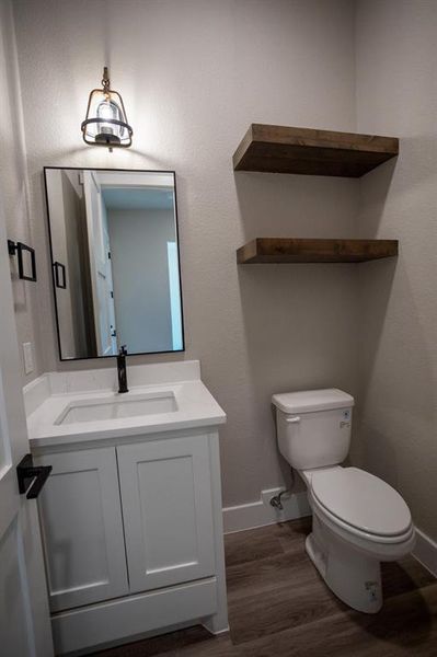 Half bath featuring vanity, dark wood-style flooring, and a textured wall Half bath featuring vanity, dark wood-style flooring, and a textured wall