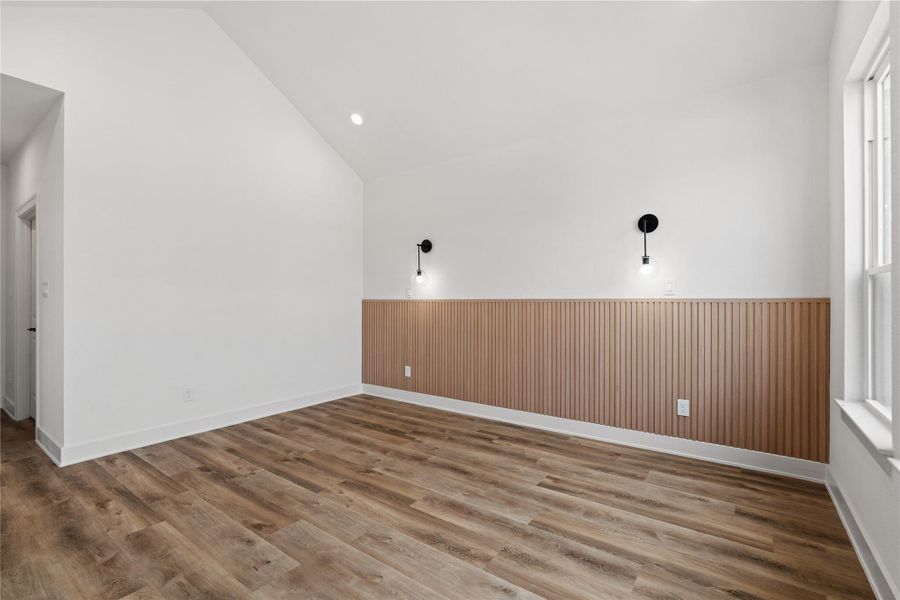 Another view of the primary suite showcasing the stylish wood accent wall and airy layout.