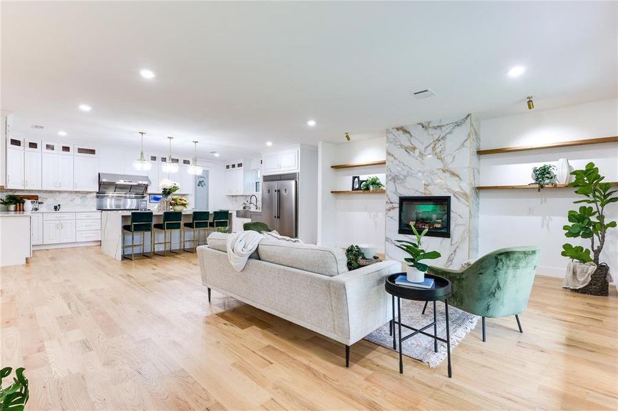 Living room featuring sink, a high end fireplace, and light wood-type flooring