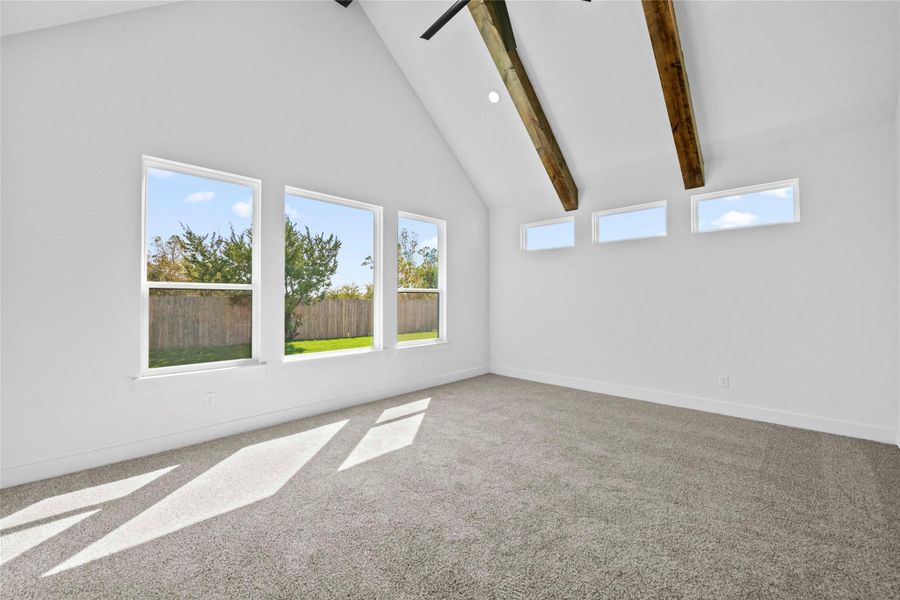 Empty room with high vaulted ceiling, beam ceiling, carpet floors, and a ceiling fan Empty room with high vaulted ceiling, beam ceiling, carpet floors, and a ceiling fan