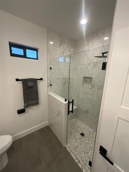 Full bathroom with a marble finish shower and toilet Full bathroom with a marble finish shower and toilet