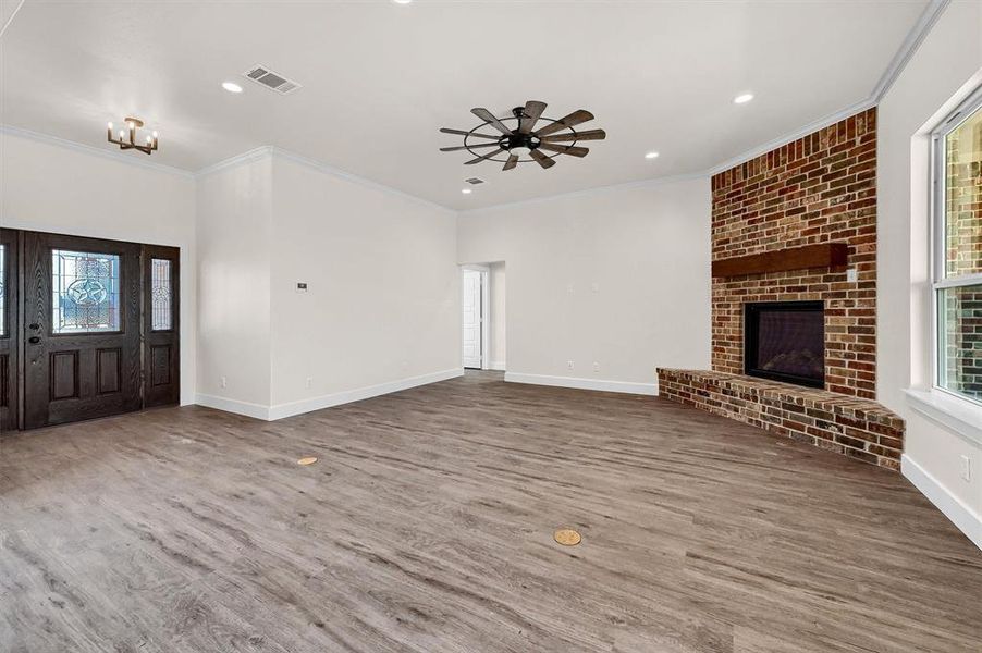 Unfurnished living room with a fireplace, ceiling fan, crown molding, and wood-type flooring