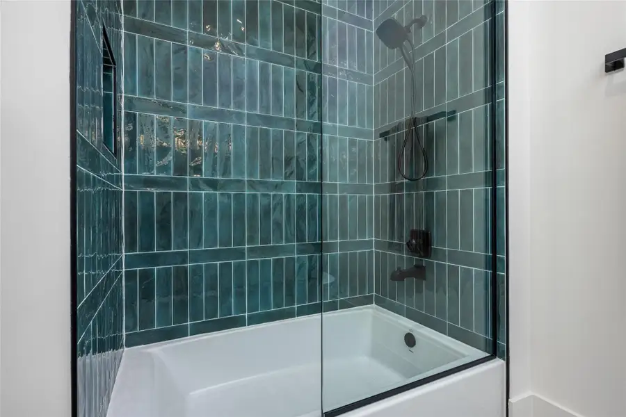 The en suite bath features a wide soaking tub, porcelain backsplash, quartz countertops, custom mirrors, and ambient vanity lighting