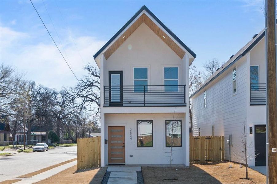 Modern home featuring fence, a balcony, and stucco siding