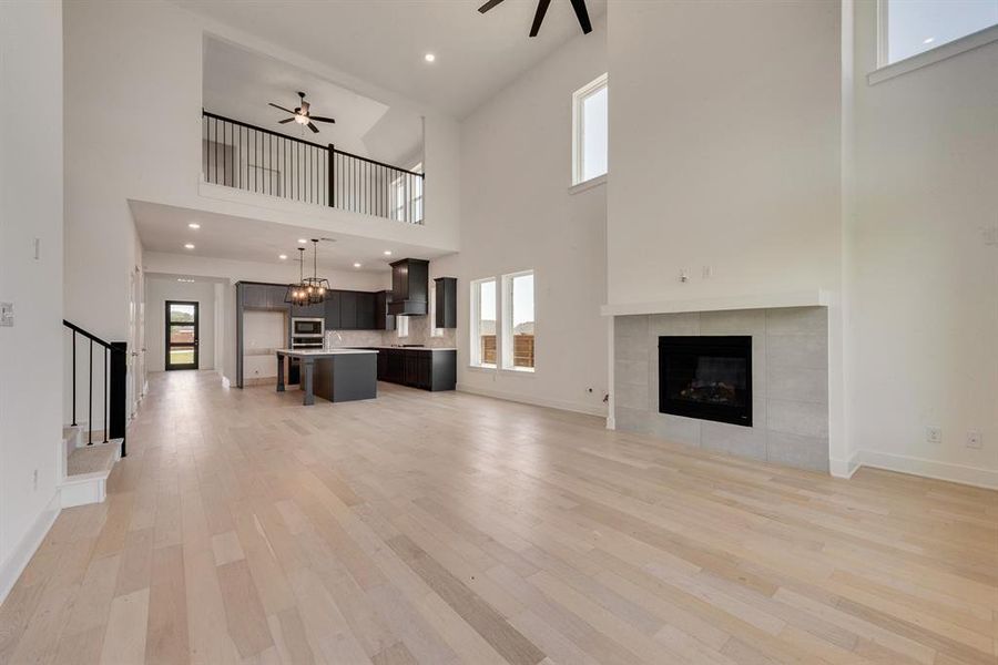 Unfurnished living room with a fireplace, a ceiling fan, light wood finished floors, recessed lighting, and stairs Unfurnished living room with a fireplace, a ceiling fan, light wood finished floors, recessed lighting, and stairs