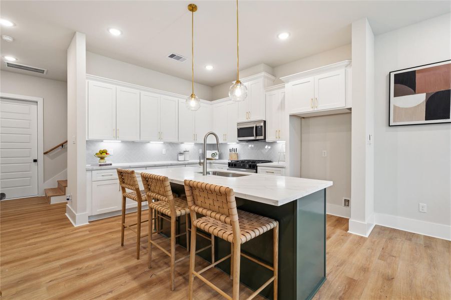 A refined kitchen anchored by a rosemary green accent island, layered with brass hardware and pendant lighting. Herringbone tile, under mount lighting, and soft close cabinetry complete the space with both warmth and precision. A refined kitchen anchored by a rosemary green accent island, layered with brass hardware and pendant lighting. Herringbone tile, under mount lighting, and soft close cabinetry complete the space with both warmth and precision.