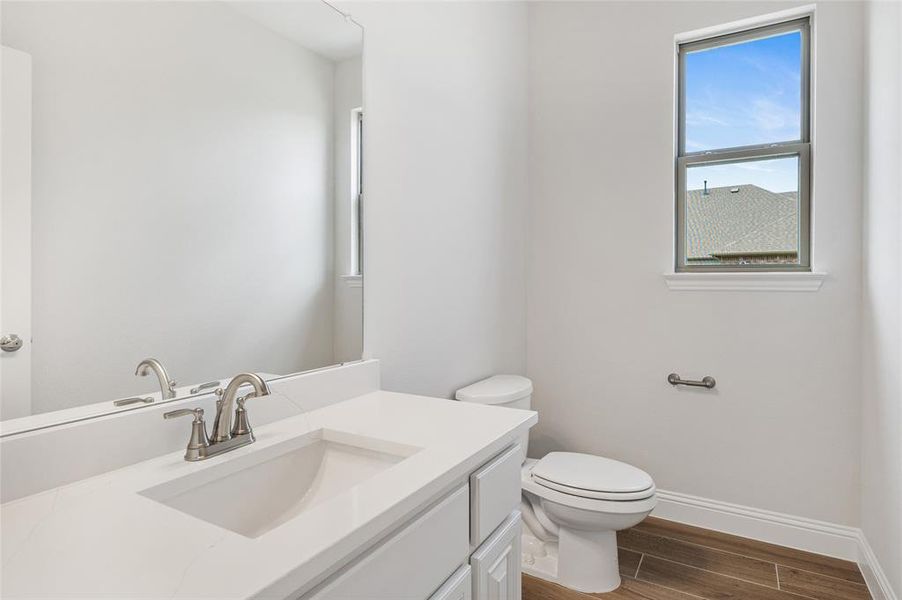Half bathroom featuring wood finish floors and vanity