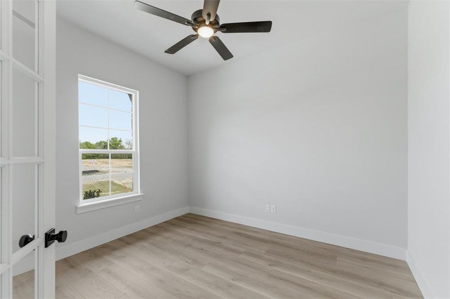 Unfurnished room with light wood-style floors, ceiling fan, and french doors