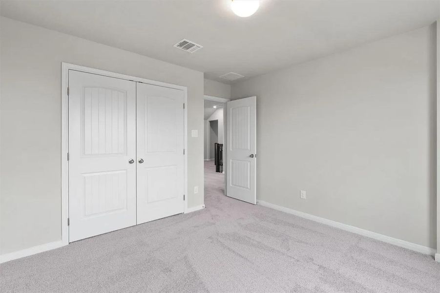 A well-lit bedroom features ample closet space and plush carpeting, ready for personalization.