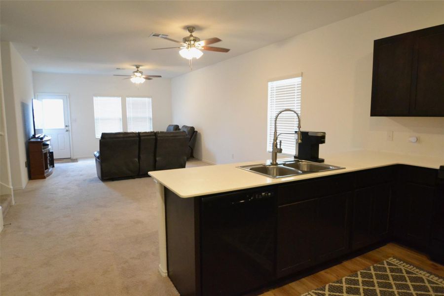 Kitchen featuring dishwasher, a peninsula, light countertops, open floor plan, and a ceiling fan