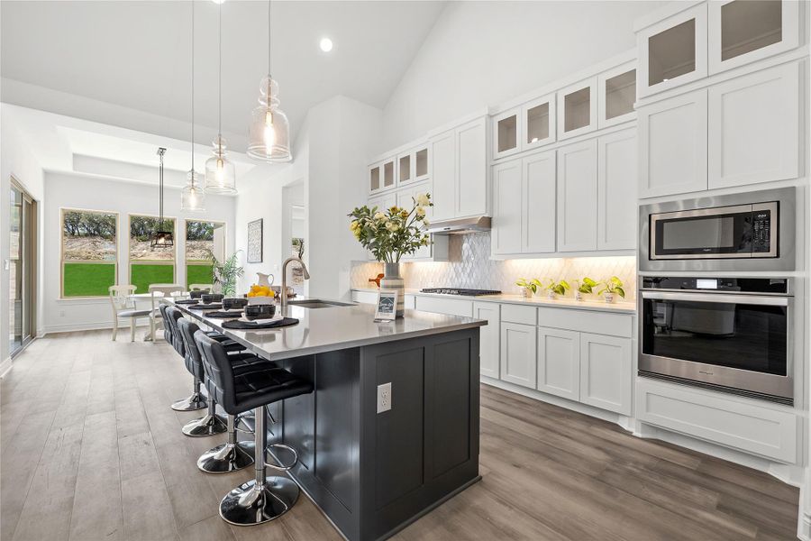 Kitchen featuring decorative backsplash, stainless steel appliances, dark wood-style floors, a center island with sink, and white cabinetry
