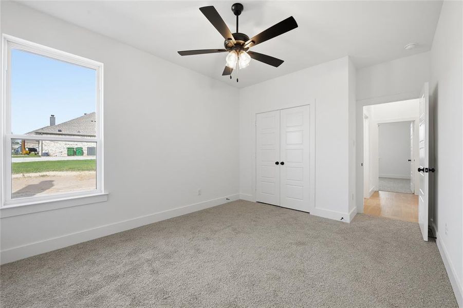 Unfurnished bedroom with light carpet, a closet, and ceiling fan Unfurnished bedroom with light carpet, a closet, and ceiling fan