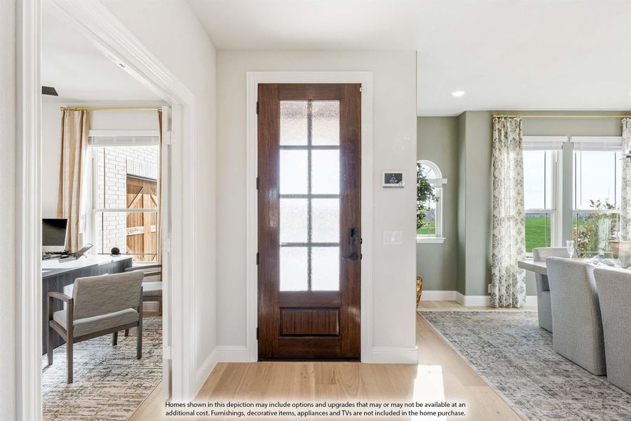 Entryway with dark wood front door featuring glass panels, light hardwood floors, and open views to home office and living room. Entryway with dark wood front door featuring glass panels, light hardwood floors, and open views to home office and living room.