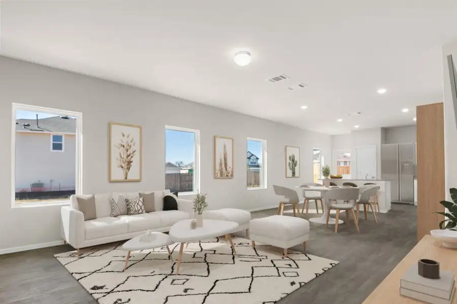 Image of a living room staged photo with a white couch and coffee tables, a white rig, wall decor, and a round dinner table