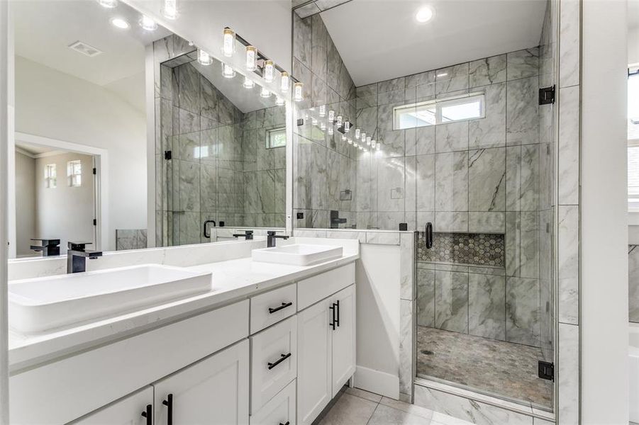 Bathroom with vaulted ceiling, tile patterned floors, walk in shower, and double vanity