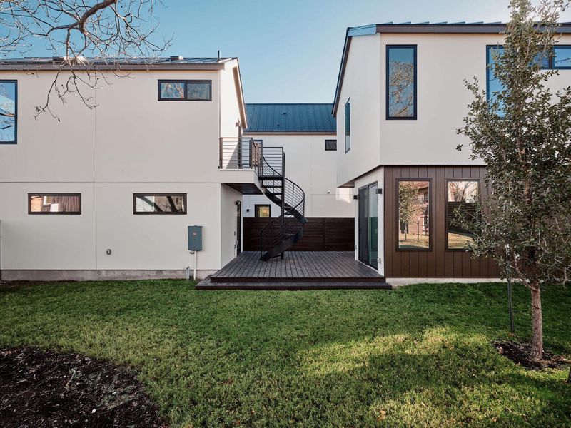 Rear view of property featuring a metal roof, a deck, a lawn, and stairs