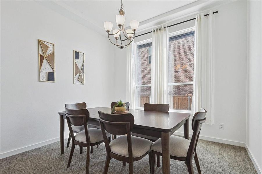 Dining room with carpet floors and an inviting chandelier