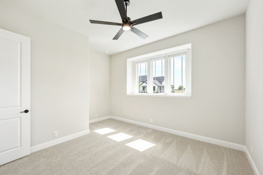 Empty bedroom with beige carpet, black ceiling fan, and a triple-pane window with neighborhood view Empty bedroom with beige carpet, black ceiling fan, and a triple-pane window with neighborhood view