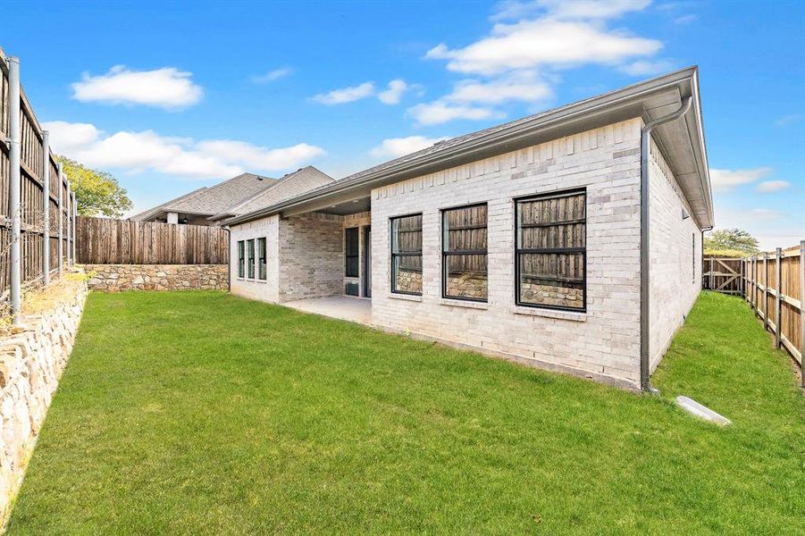 Rear view of property featuring brick siding, a patio, and a fenced backyard