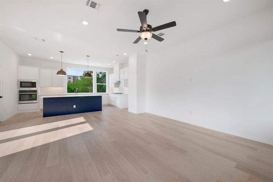 Spacious open-concept living area featuring light wood-finish flooring and recessed lighting