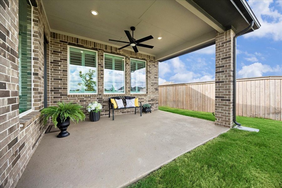 This covered patio expands your living space, featuring recessed lighting, a ceiling fan, and stylish brick accents. Enjoy seamless indoor-outdoor living through a wall of windows, with a gas hook-up ready for your dream outdoor kitchen. The patio overlooks the backyard, offering peaceful views of the water and trails.