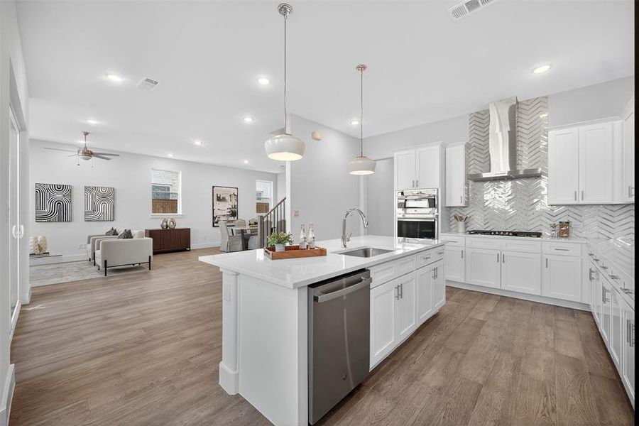 Kitchen with backsplash, white cabinets, pendant lighting, appliances with stainless steel finishes, and light wood-type flooring Kitchen with backsplash, white cabinets, pendant lighting, appliances with stainless steel finishes, and light wood-type flooring