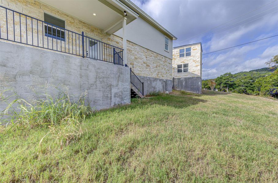 View of grassy yard featuring stairway and a balcony