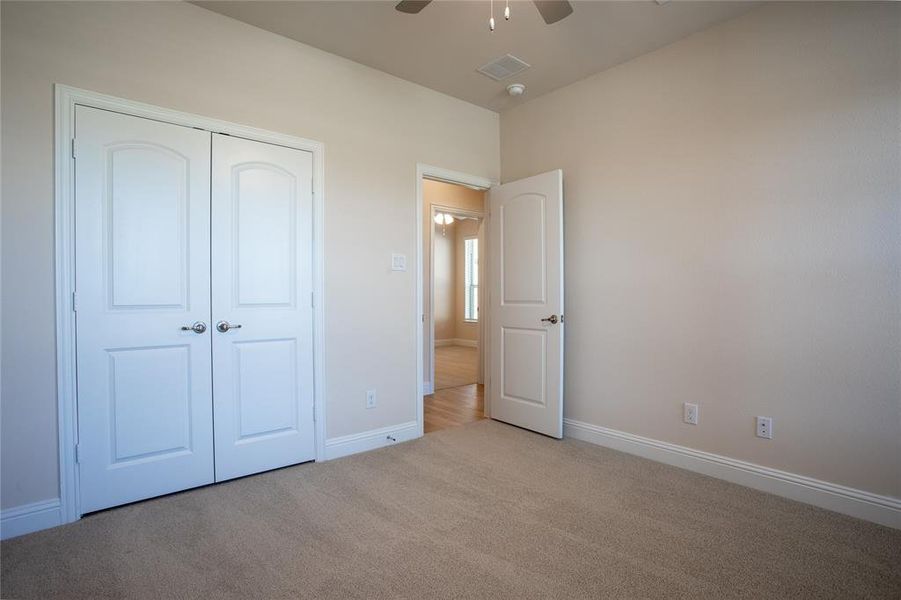 Unfurnished bedroom with a closet, ceiling fan, and light colored carpet