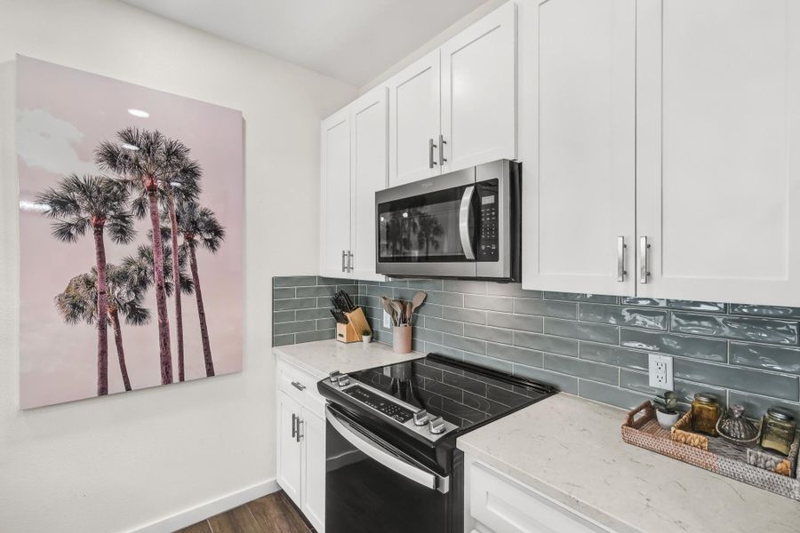 Kitchen with electric range oven, light stone counters, tasteful backsplash, and stainless steel microwave Kitchen with electric range oven, light stone counters, tasteful backsplash, and stainless steel microwave