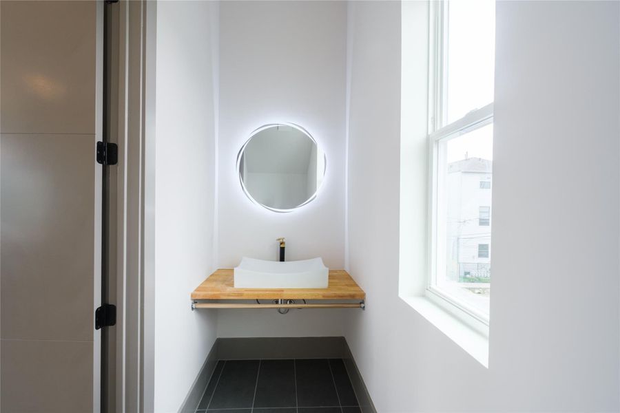 Representative Bathroom View (Design selections and colors may vary): Every full bath in the home includes custom-designed wood vanities, vessel sinks, and functional open shelving, offering continuity in design and quality.
