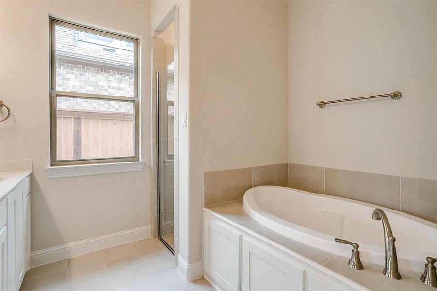 Bathroom featuring plus walk in shower, vanity, and tile patterned floors