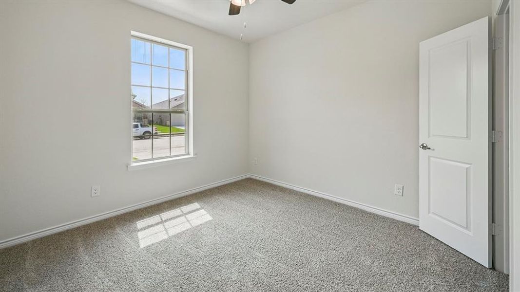 Carpeted empty room with a ceiling fan and baseboards