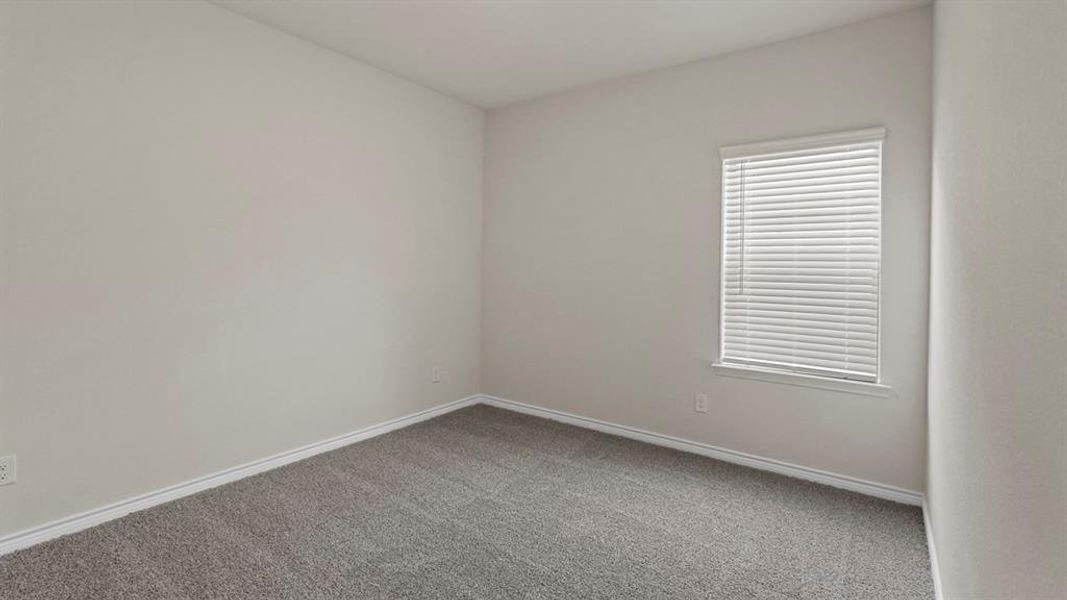 Neutral-toned room featuring a single window with blinds, light gray walls, and gray carpeting