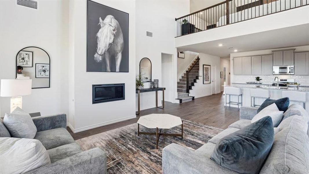 Living area featuring a high ceiling, dark wood-style floors, a glass covered fireplace, and recessed lighting