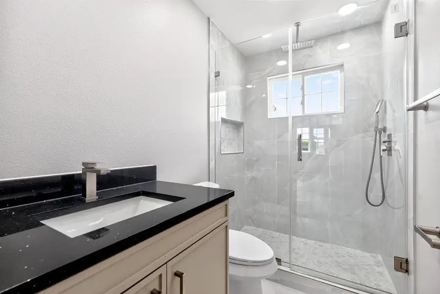 Full bathroom featuring vanity, a marble finish shower, and a textured wall Full bathroom featuring vanity, a marble finish shower, and a textured wall