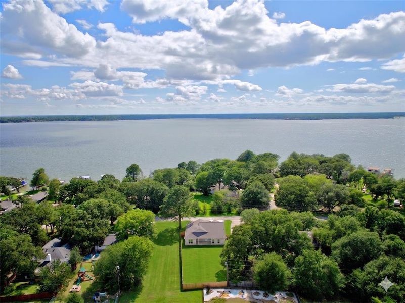 Expansive water frontage with mature trees and a manicured lawn